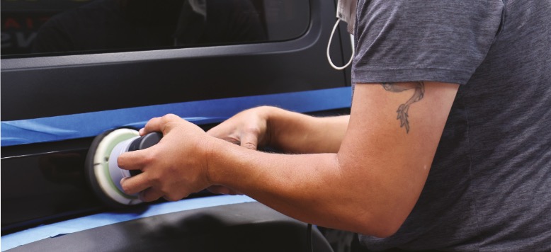 Student working on paint correction on side of SUV.