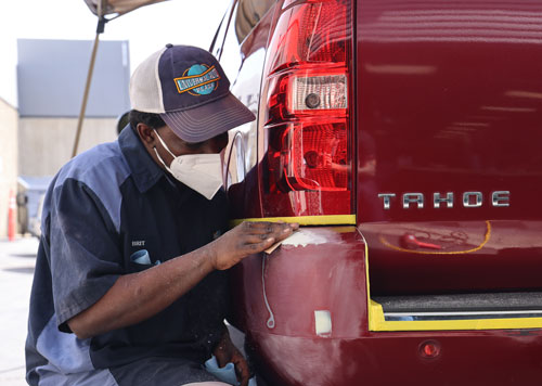 Student taking scuffed bumper repair training course at The Ding King.