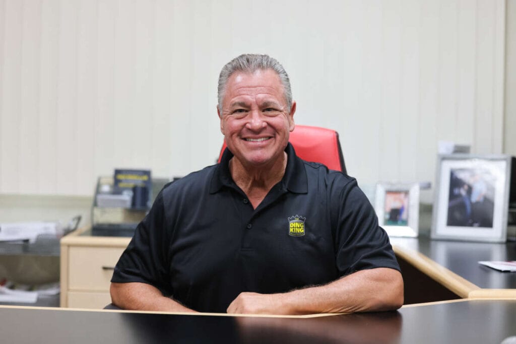 Meet the King A smiling man sitting at a desk in an office.