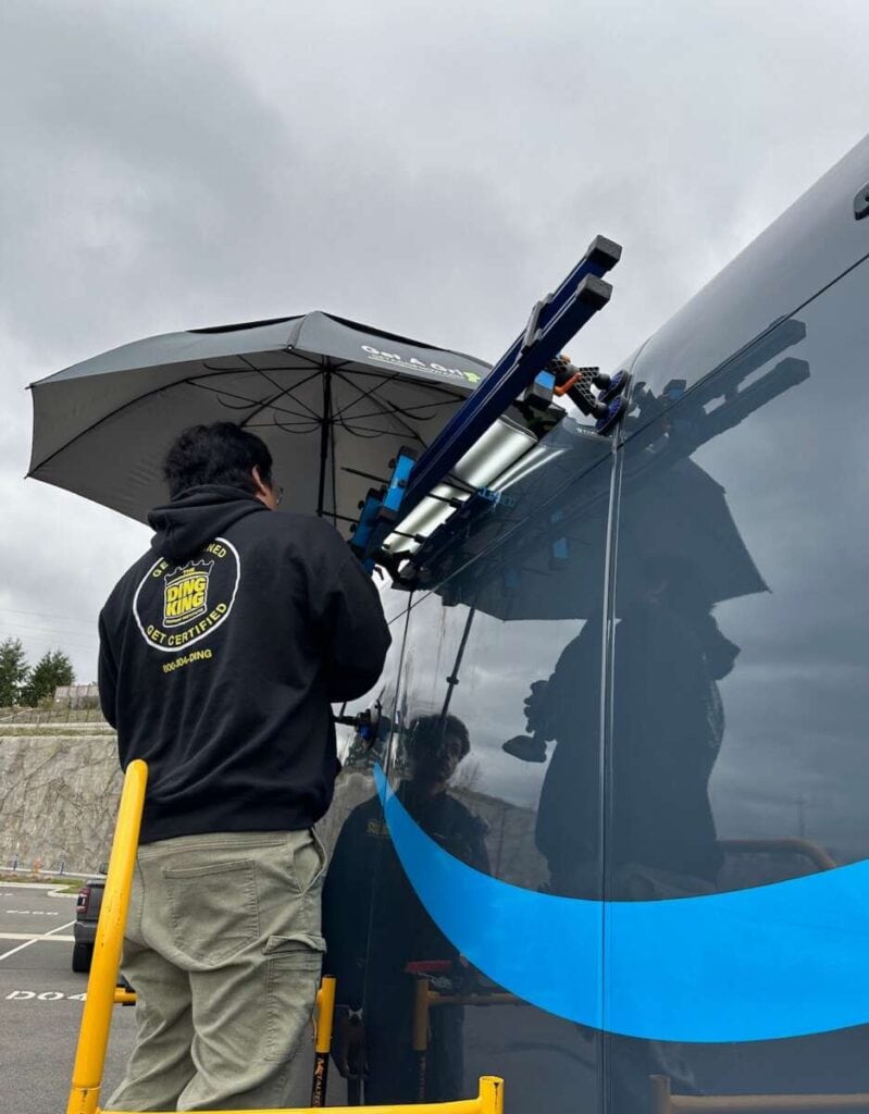 Person conducting maintenance on a bus with a telescopic device in an automotive business opportunity.