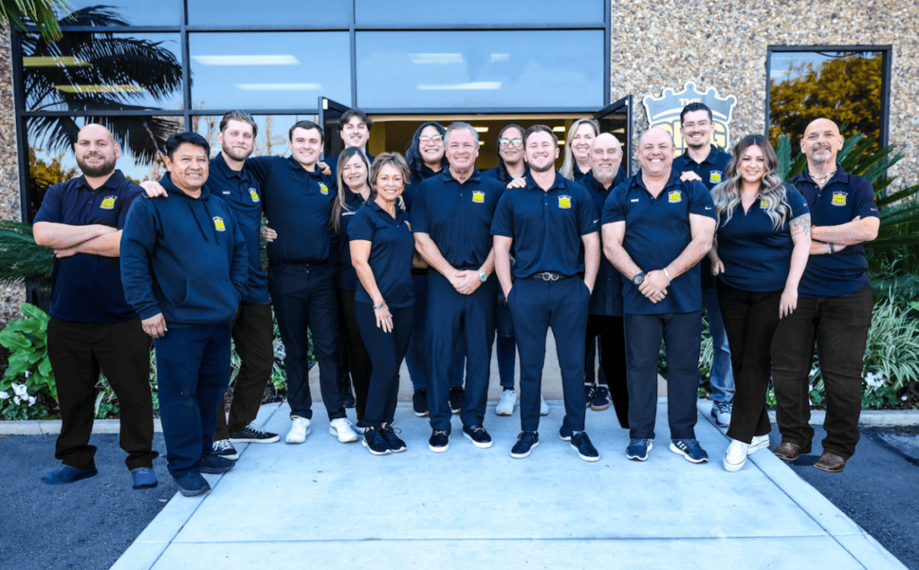 Group of professionals in matching uniforms posing for a team photo outside an office building.