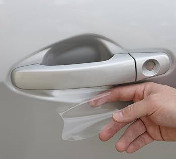 A hand expertly removes a transparent Paint Protection Film from the underside of a car door handle, showcasing the effectiveness of proper training.