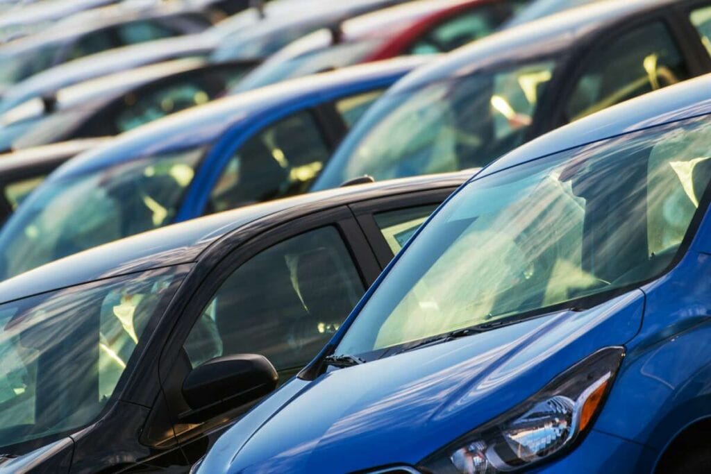 A close up view of the front sections of multiple parked cars in a lot, with various colors and models visible, arranged in neat rows, showcasing attention to detail often emphasized in Advanced PDR Training sessions.