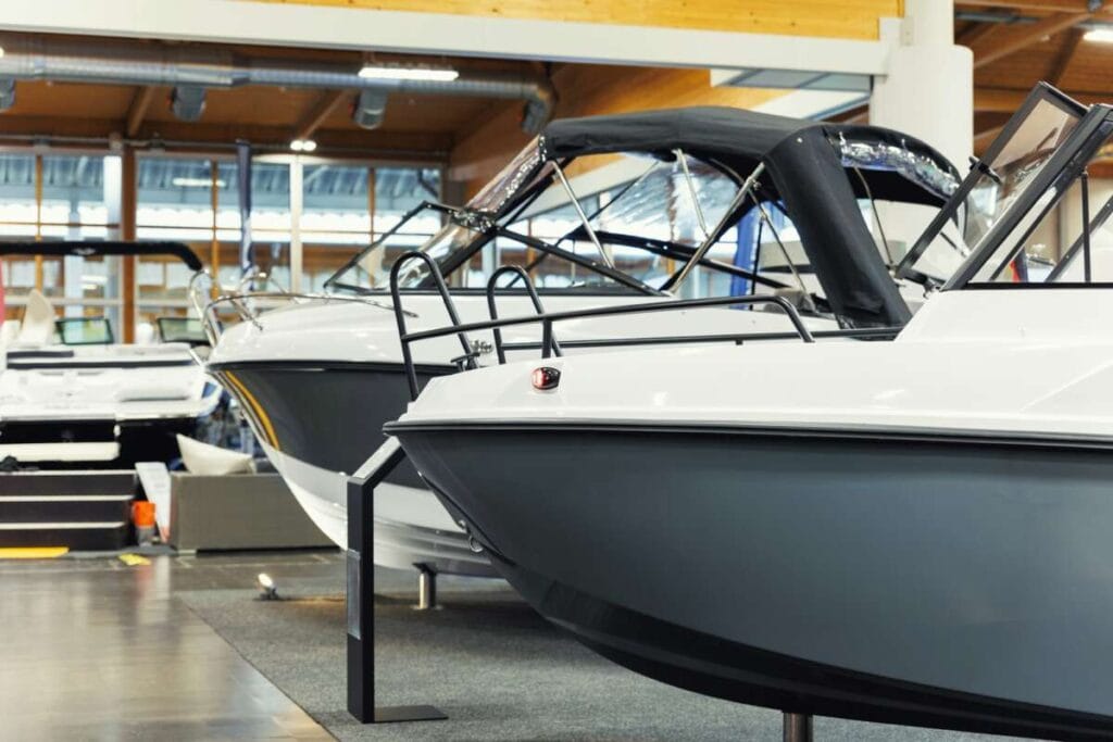 Several sleek, modern boats with black and white color schemes are displayed indoors on a sales floor, showcasing the perfect candidates for Paint Protection Film training.