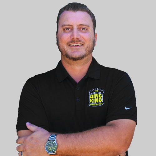 Meet the team: A man with short hair in a black polo shirt with the "Ding King" logo, arms crossed and smiling, against a light grey background.