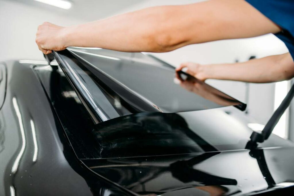 Male specialist with car tinting film in hands