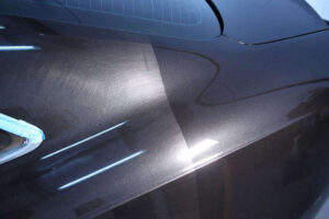 Car surface showing a side by side comparison of polished and unpolished paint, highlighting the contrast in shine and smoothness.